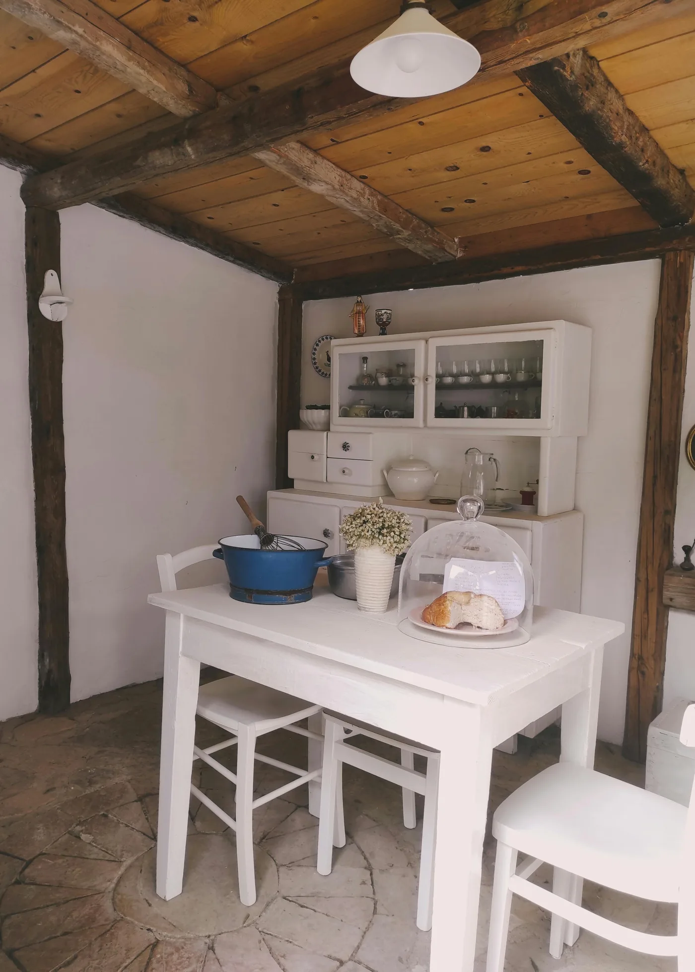 Cocina y comedor blancos con vigas de madera en ambiente rural